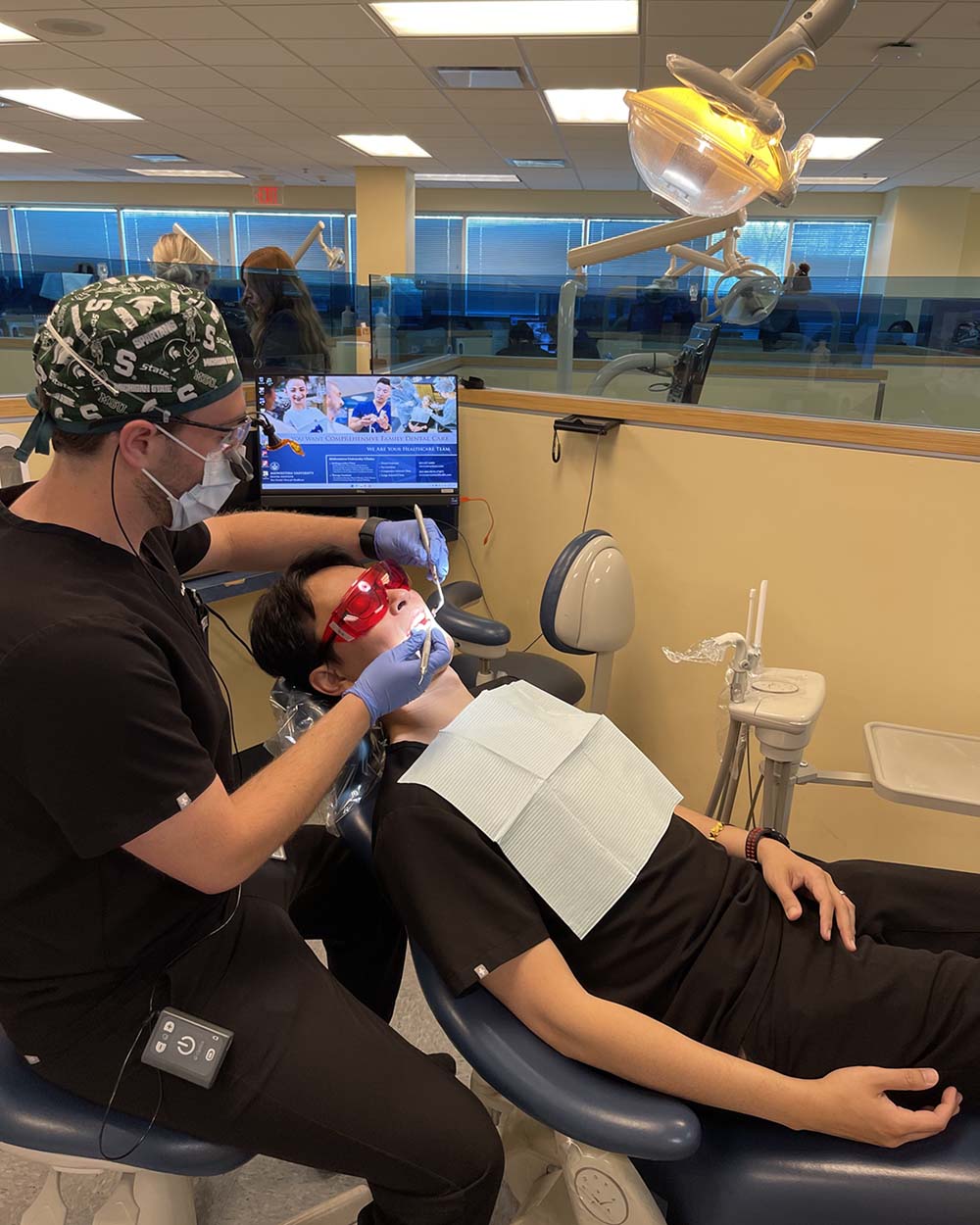 Matthew Williams doing dentistry in Spartan-themed scrub cap 