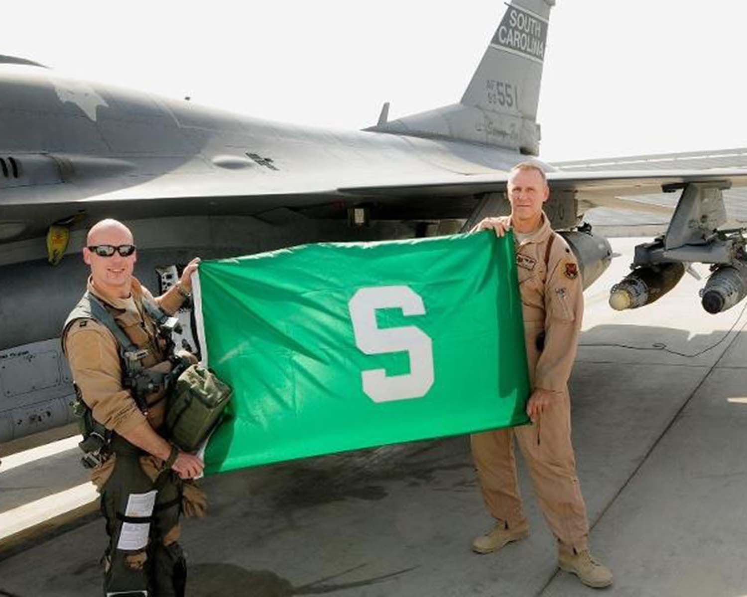 Thomas Watts and other pilot with MSU flag in front of airplane