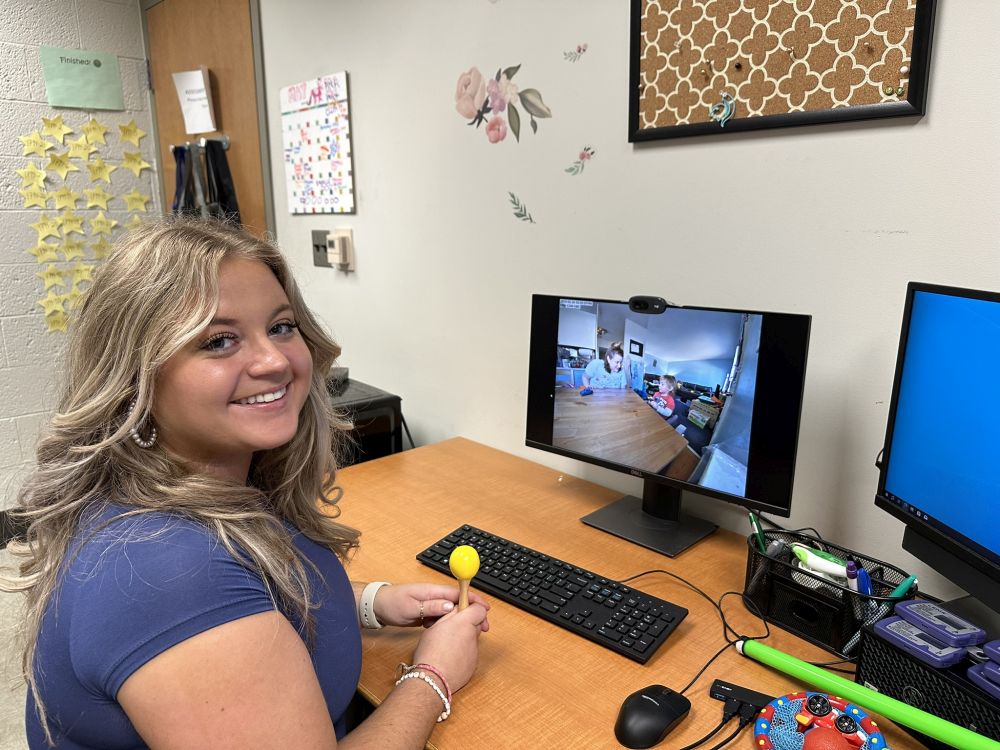 Jessie Greatorex demonstrates an activity where she shakes a maraca and says, “You do it!” The parent would do the same thing, hand the maraca to the child, then see if the child shakes the maraca too.