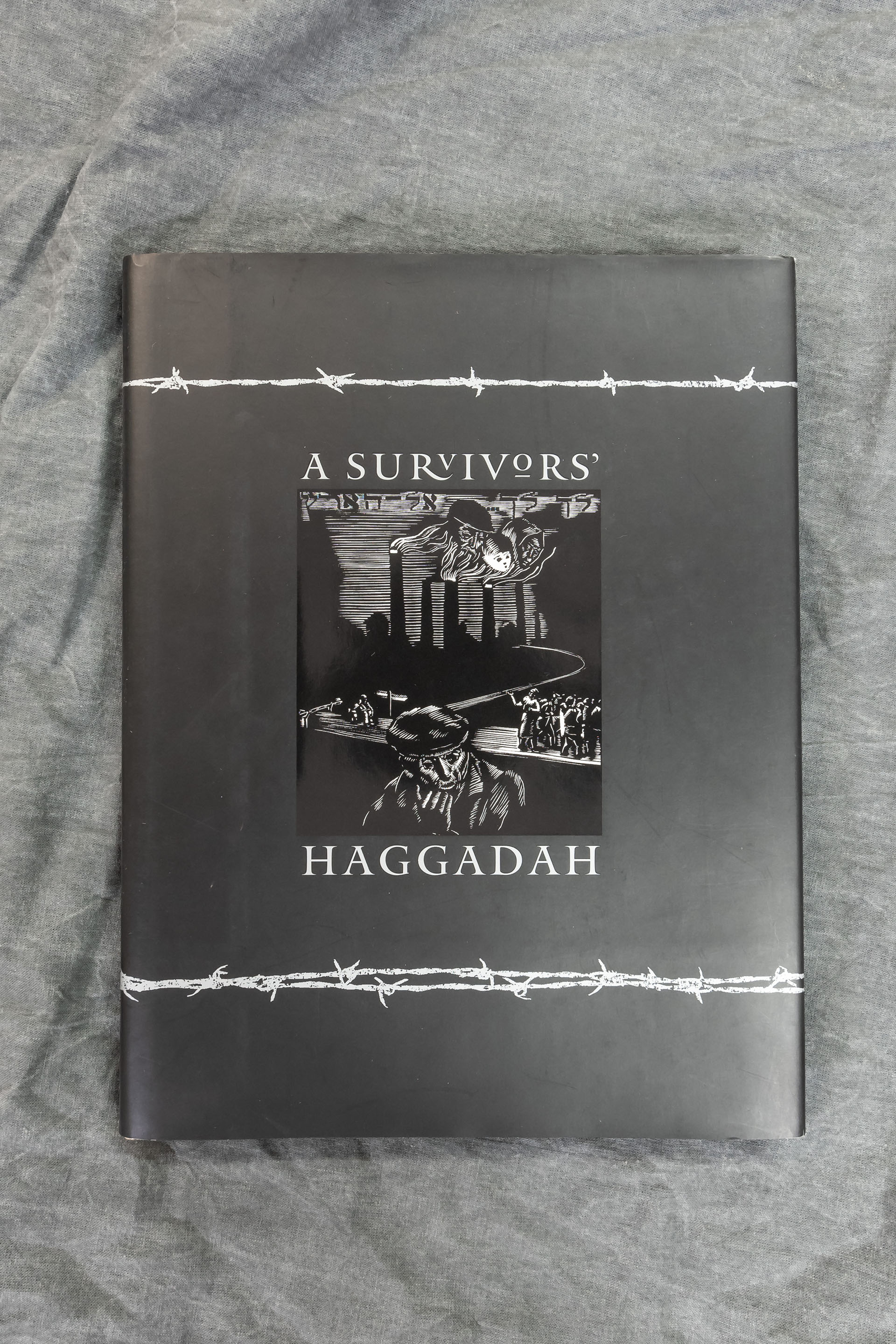 Haggadah book cover featuring barbed wire and black and white illustrations