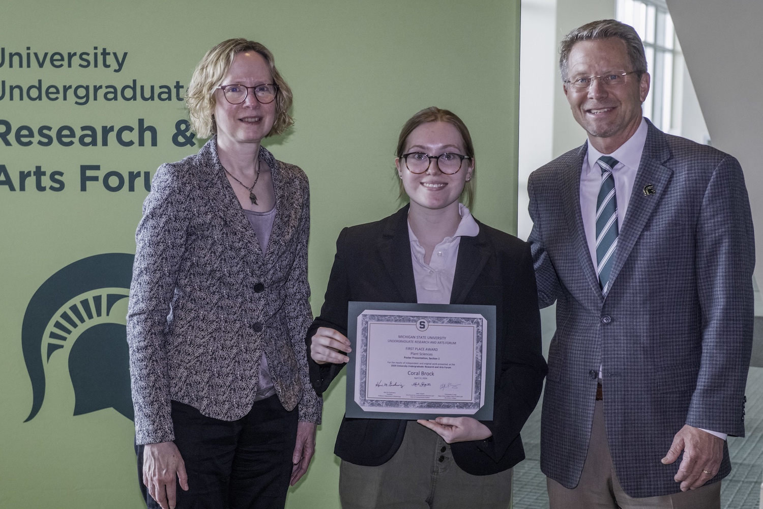 Coral Brock holds a certificate from UURAF along with Michigan State University President Kevin M. Guskiewicz and Lynmarie Posey, associate dean for Undergraduate Studies in College of Natural Science