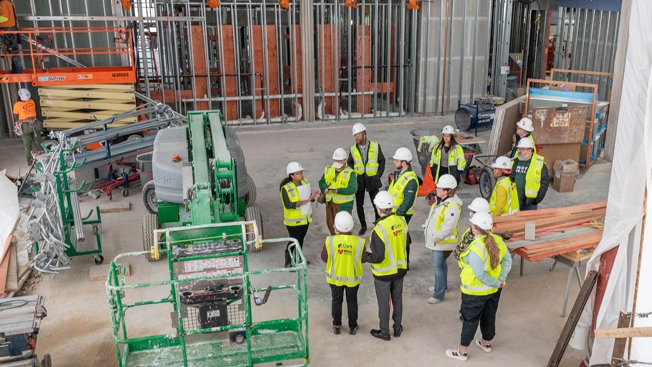 A group of people in reflective vests and hard hats on a construction floor.