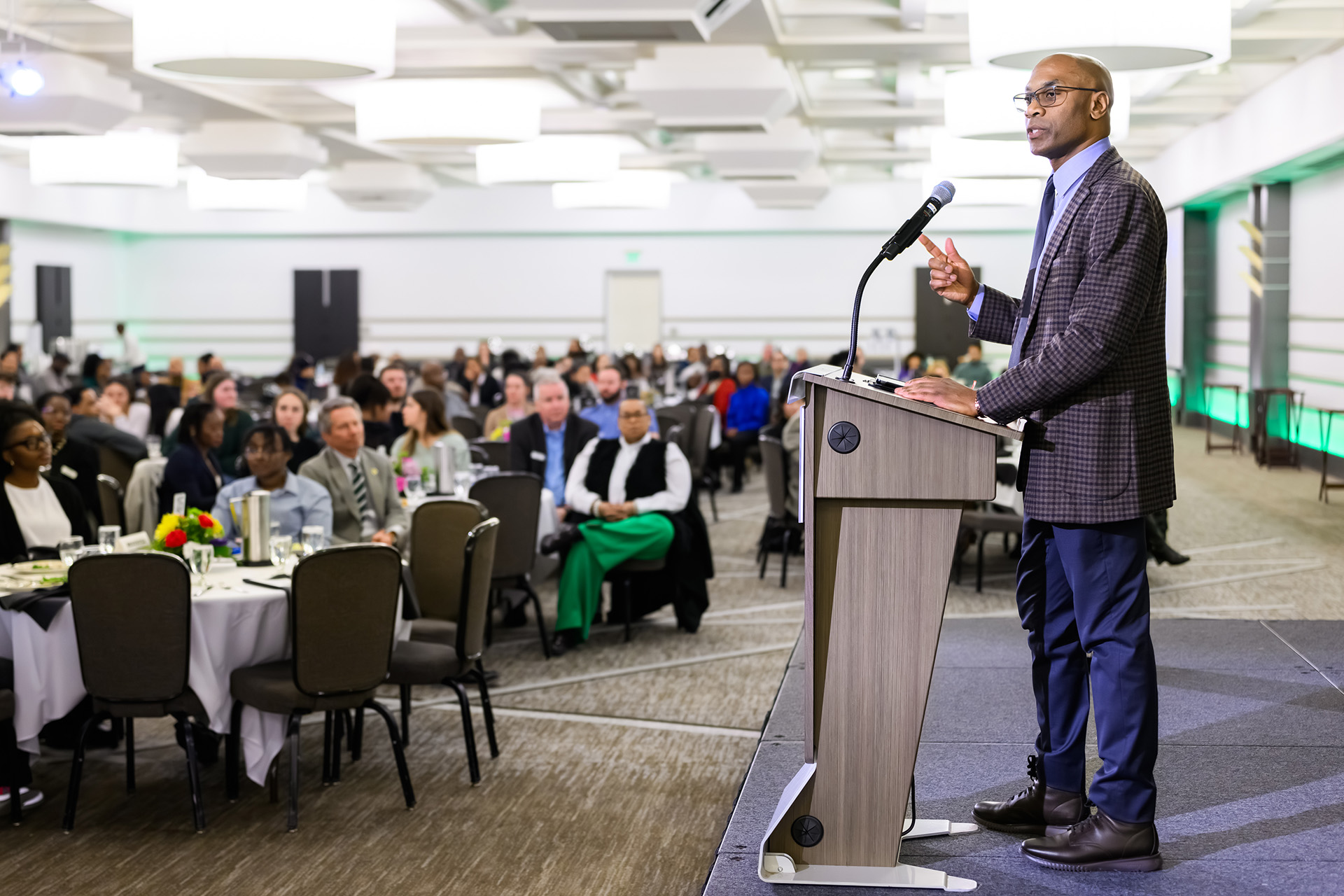 Chief Diversity Officer Jabbar Bennett stands at the lectern providing closing remarks to a filled large room