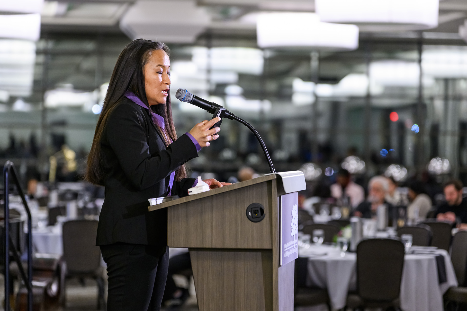 Sharon Chia Claros reads from a phone, delivering the 2025 MLK keynote from the lectern