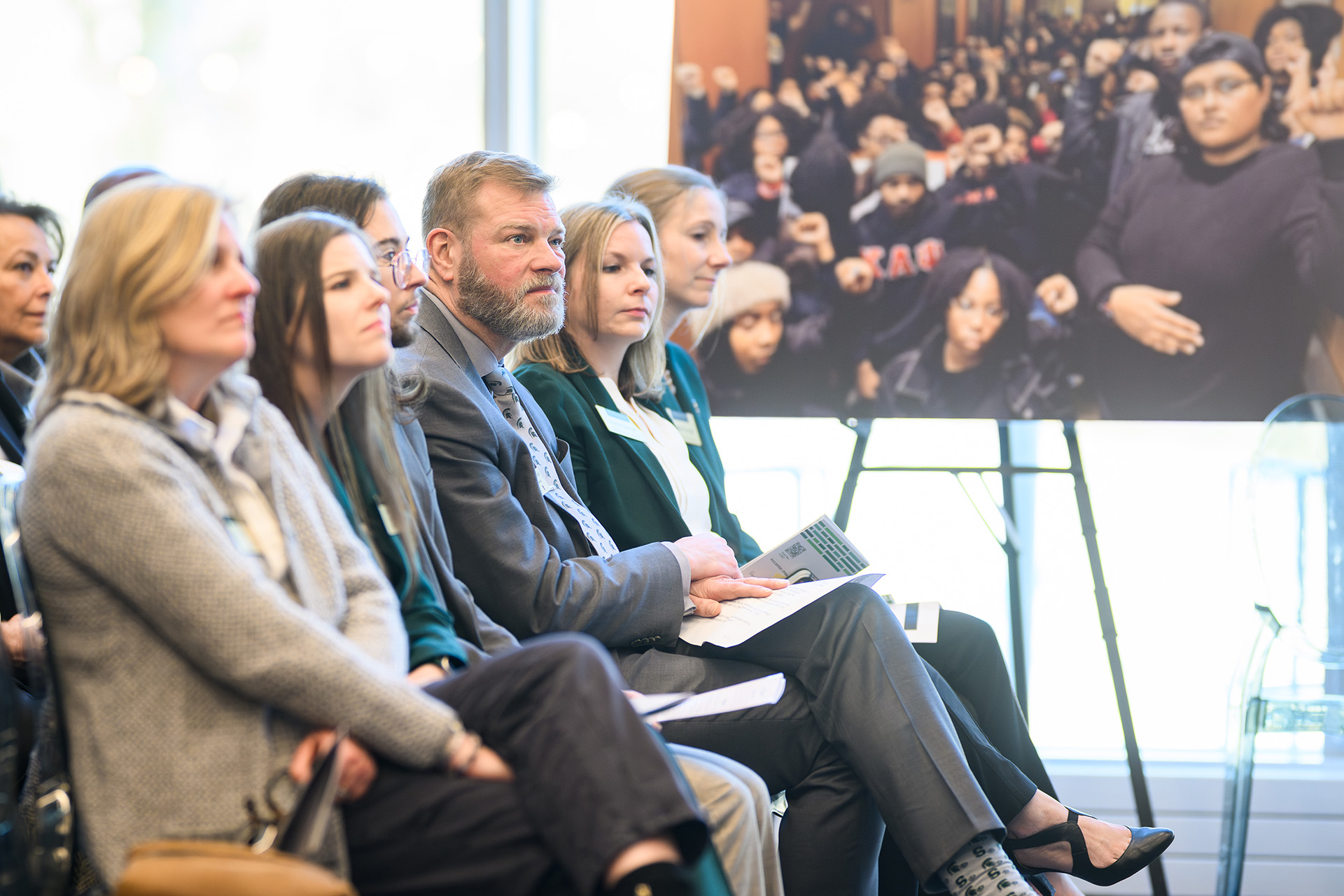 leaders sitting in a row with a poster of advocacy in the background