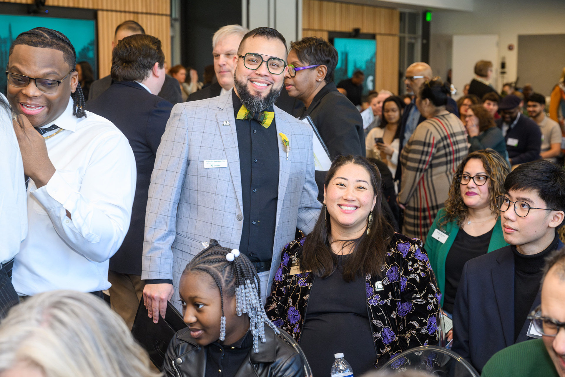 Two alums smile in a crowded room