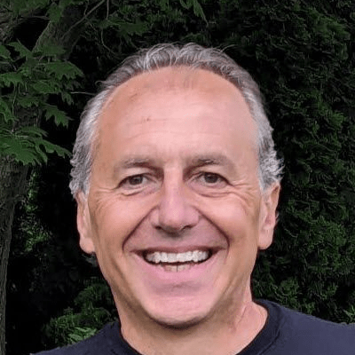Bruno Basso smiling outdoors with trees in the background, wearing a black shirt.