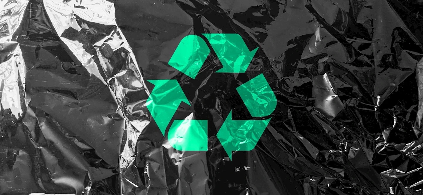 A green recycling logo over a slate grey foil that is wrinkled